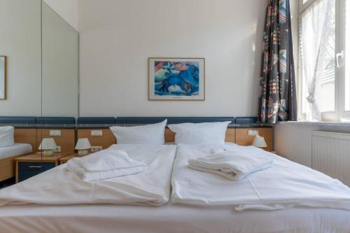 ein weißes Bett mit zwei Handtüchern darauf in der Unterkunft Villa Sirene 2-Raum Apartment, ca. 54 qm in Binz