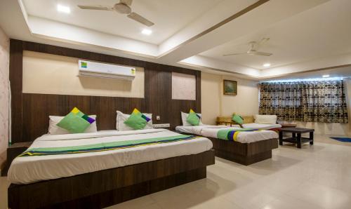 a hotel room with two beds and a television at Itsy Hotels Shree Krishna Palace in Ahmedabad
