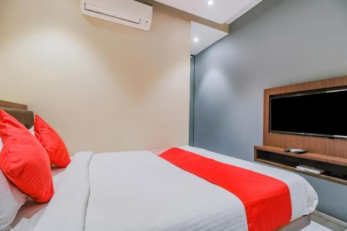 a bedroom with a bed with red pillows and a flat screen tv at Flagship 79617 Hotel Ahlan International in Mumbai