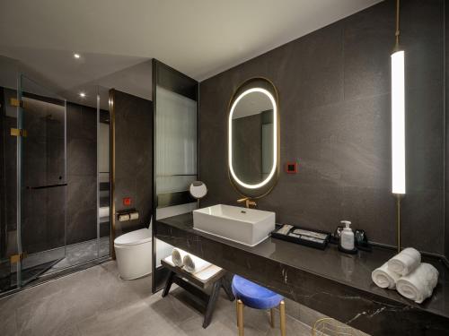 a bathroom with a sink and a toilet and a mirror at 西安钟楼枫渡酒店永兴坊地铁站店 in Xi'an