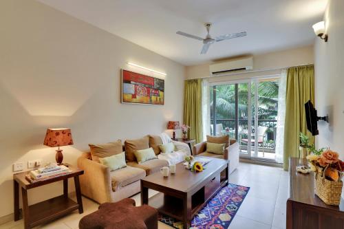 uma sala de estar com um sofá e uma mesa em Veeraas Calangute - 2BHK Apartment with Pool em Marmagao