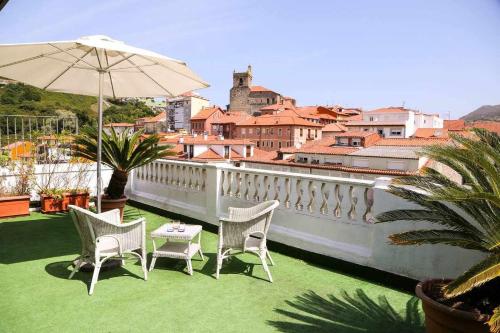 d'une terrasse avec des chaises et un parasol sur le balcon. dans l'établissement ático vistas centro 3min playaparking y wifi free, à Laredo