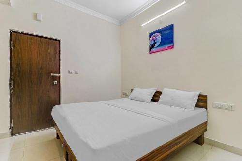 a bedroom with a white bed with a wooden door at Capital O Safari Rooms Near Snow City in Bangalore