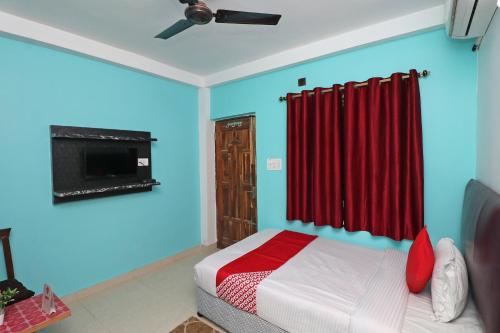 ein Schlafzimmer mit einem Bett mit einem roten Vorhang in der Unterkunft OYO Flagship Fun Friday Guesthouse in Bodh Gaya