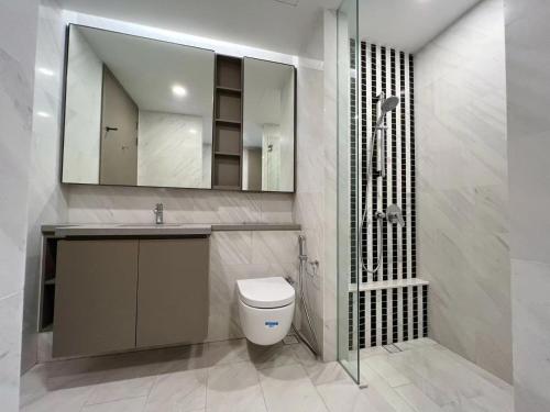 een badkamer met een toilet, een wastafel en een spiegel bij Eaton Suites KLCC by QC in Kuala Lumpur