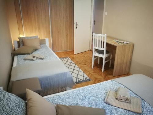 a small room with two beds and a desk at Fontana Apartman in Makó