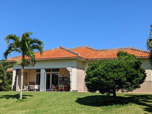 a house with a palm tree in the yard at Beachfront Paradise Ishigaki in Ishigaki Island