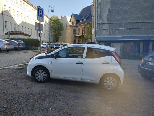 a small white car parked on the side of a street at Pokoje gościnne w centrum in Wałbrzych