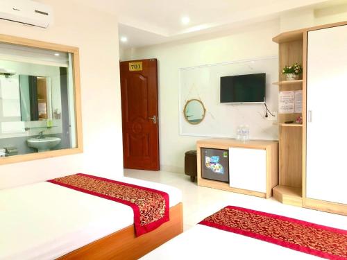 uma sala de estar com uma cama e uma televisão em Sail Hotel Hạ Long em Ha Long