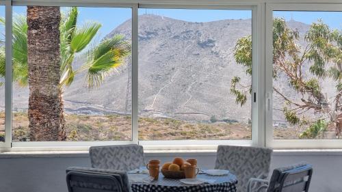 a table and chairs with a view of a mountain at Villa Azure Horizon and Breeze - Panoramic Ocean View and Heated Pool in Chayofa