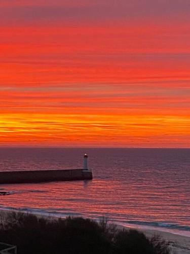 - un coucher de soleil sur l'océan avec une jetée et un phare dans l'établissement Villa Trouz Ar Mor, à Audierne