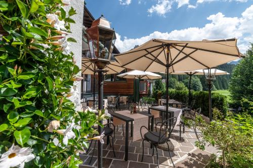 a patio with tables and chairs and umbrellas at Romantik Hotel Santer in Dobbiaco