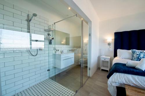 a bathroom with a shower and a bed and a sink at Struisbaai Apartments in Struisbaai