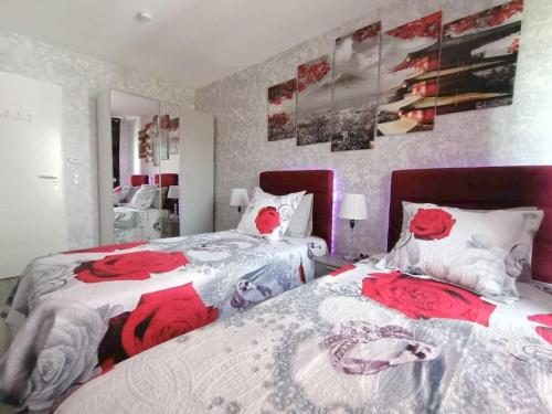 ein Schlafzimmer mit zwei Betten mit roten Rosen in der Unterkunft Appartement 4 pièces - La Rose des Yvelines - Classé 3 étoiles in Trappes