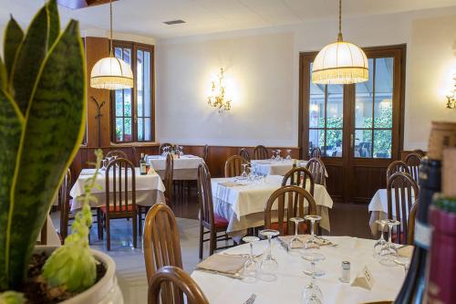 a restaurant with white tables and chairs and windows at Casa Franciacorta in Gussago