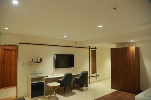 een woonkamer met een tafel en stoelen en een televisie bij Grand Manor Suites in Hyderabad