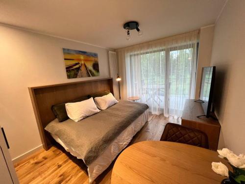 a small bedroom with a bed and a table at Cosy apartment with a balcony by the sea. in Ķesterciems