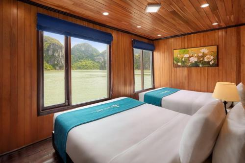 two beds in a room with a window at Cozy Bay Cruise in Ha Long