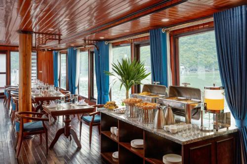 a restaurant with tables and chairs and windows at Cozy Bay Cruise in Ha Long