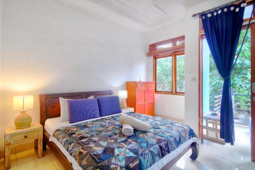 a bedroom with a bed with blue pillows at Bamboo Paradise in Padangbai