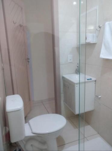 a white bathroom with a toilet and a sink at Suíte alvenaria casal. in Guabiruba
