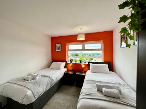 two beds in a room with an orange wall at Havenwood House - Great for Contractors or Family Holidays in Nottingham
