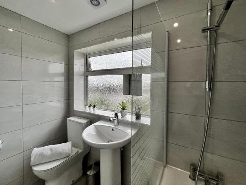 a bathroom with a sink and a toilet and a shower at Havenwood House - Serene Escape Cottage in Nottingham