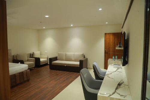 Habitación con sala de estar con sofá y sillas. en Grand Manor Suites, en Hyderabad