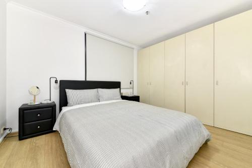 a white bedroom with a large bed and white cabinets at Beautiful apartment in Pyrmont in Sydney