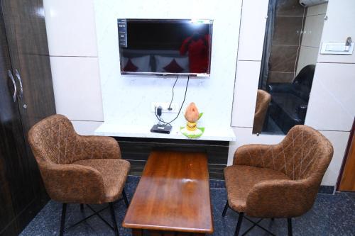 um quarto com duas cadeiras e uma mesa e uma televisão em ESHANNA RESIDENCY em Davanagere