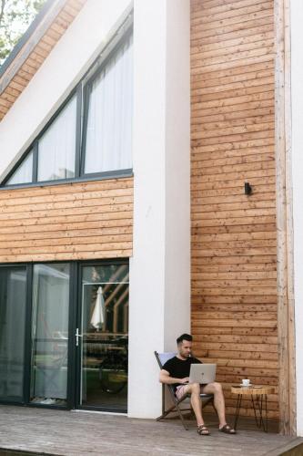 a man sitting in a chair with a laptop at Vacanza Park in Łeba