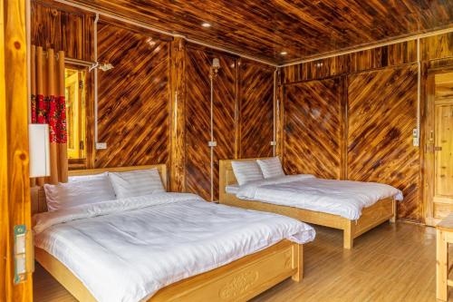 - 2 lits dans une chambre dotée de murs en bois dans l'établissement Hoa Chanh Eco Home, à Sa Pa