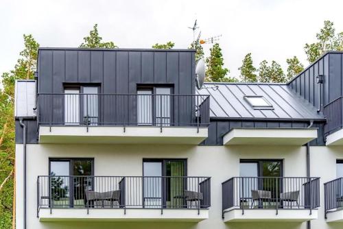 a house with a black roof and balcony at Natura Mierzei 30 - pokoje przy plaży in Krynica Morska