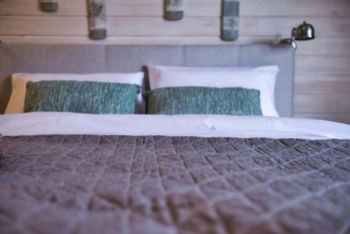 a large bed with two green pillows on it at Natura Mierzei 30 - pokoje przy plaży in Krynica Morska