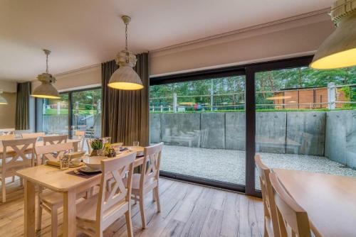 a restaurant with tables and chairs and a large window at Natura Mierzei 30 - pokoje przy plaży in Krynica Morska