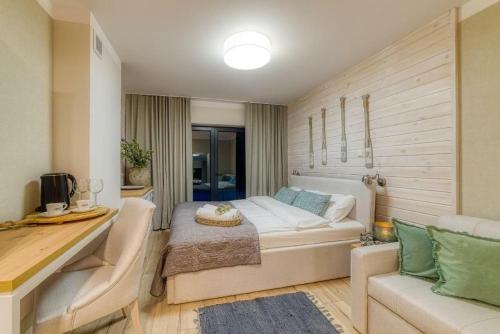 a bedroom with a bed and a desk and a couch at Natura Mierzei 30 - pokoje przy plaży in Krynica Morska
