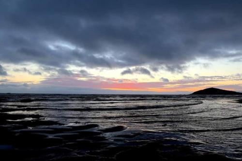 a sunset over the ocean with a mountain in the background at Quirky 2-bed flat w/ parking central Kingsbridge in Kingsbridge