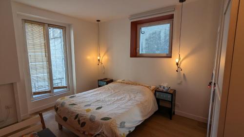 a small bedroom with a bed and two windows at "Maison verte" - terrasse - parking - 10min du métro in Montreuil