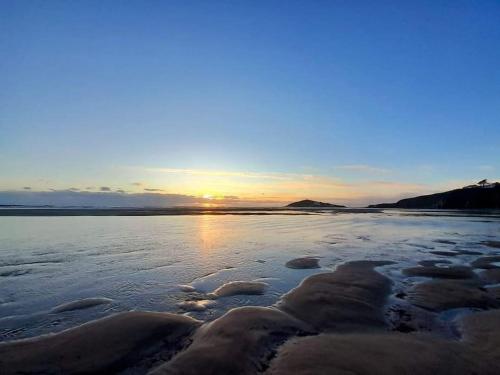 a beach with the sun setting in the horizon at Quirky 2-bed flat w/ parking central Kingsbridge in Kingsbridge