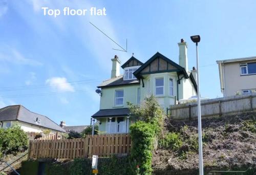 a house on top of a hill with a fence at Quirky 2-bed flat w/ parking central Kingsbridge in Kingsbridge