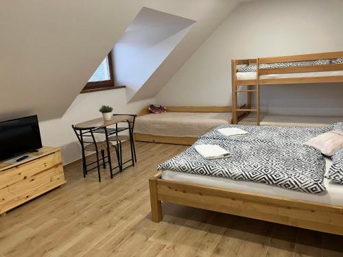 a bedroom with two bunk beds and a table and a television at Penzion U Kostela in Kuželov