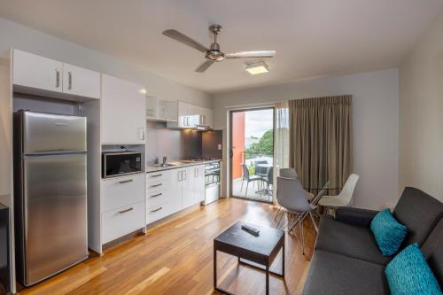a living room with a couch and a kitchen at Essence Apartments Chermside in Brisbane