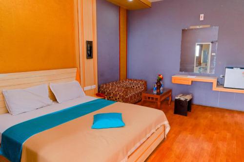 ein Schlafzimmer mit einem Bett, einem Stuhl und einem TV in der Unterkunft Hotel JK Grand in Yercaud