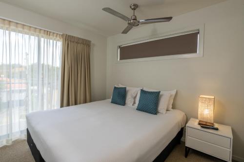 a bedroom with a large white bed with a window at Essence Apartments Chermside in Brisbane