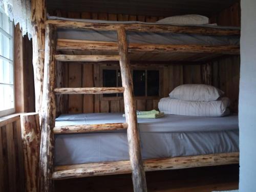 Tiny Cozy House في Pärispea: سرير بطابقين خشبي مع وسائد عليه