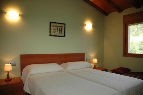 a bedroom with a large white bed with two lamps at Casa con vistas al lago y con piscina - Casó Nou in La Baronia de Rialb
