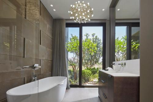 a bathroom with a tub and a sink and a chandelier at YAMA Resort in Kibbutz Ginnosar