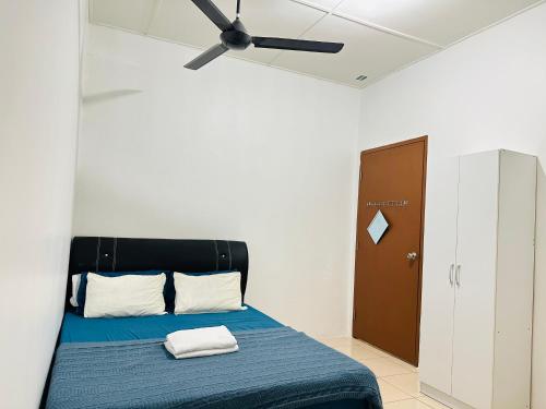 una camera con letto blu e ventilatore a soffitto di Macagawa Homestay a Tawau