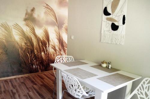 une table et des chaises blanches dans une pièce avec un tableau dans l'établissement Apartament Zacisze, à Wieliczka