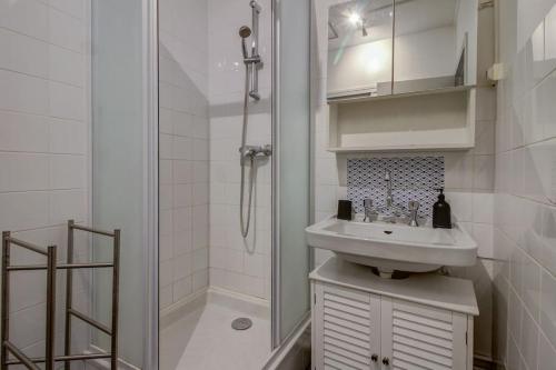 y baño blanco con lavabo y ducha. en Les Facs : Apt 6 Prs, 3 ch, Balcon et Parking, en Dijon